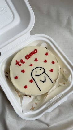 a cake in a plastic container with writing on the side and red hearts around it