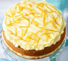 a cake sitting on top of a glass plate covered in frosting and yellow icing