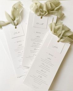 three white wedding program cards with ribbons on the top and bottom, sitting next to each other