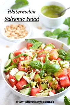 watermelon salad in a white bowl with basil and pine nuts on the side