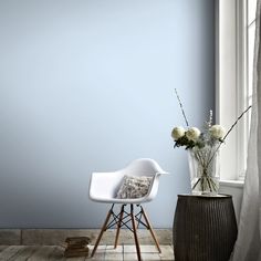 a white chair sitting next to a vase with flowers