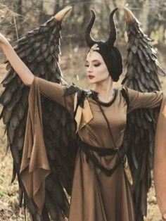 a woman dressed as an angel standing in the woods