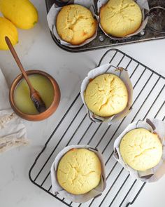 four muffins sitting on top of a cooling rack next to some lemons