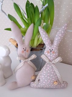 two bunny figurines sitting next to a potted plant