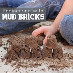 a child playing with mud bricks on the ground