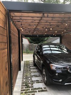 a black car parked in front of a wooden building with lights on the side of it