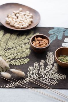 some nuts are in bowls on a table with other food items and plants around them