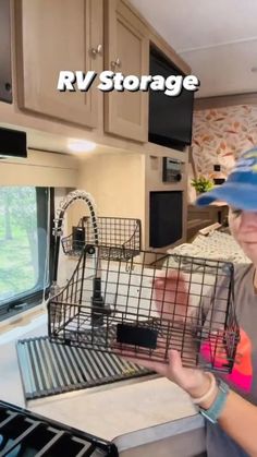 a woman holding a bird cage in her hand while standing next to an rv kitchen