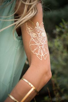 a woman's arm with gold tattoos on it