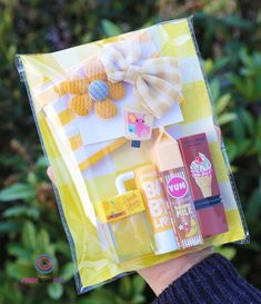 a person holding up a yellow bag with various items in it and a bow on the top