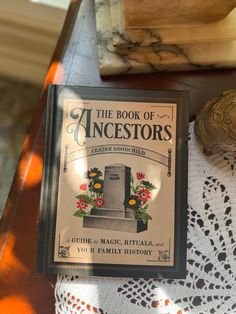 an old book sitting on top of a wooden table next to a vase with flowers