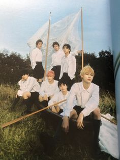 a group of young men sitting next to each other on top of a grass covered field