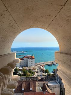 the view from an arched window looking out at a harbor and buildings in the distance