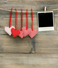 red and white hearts hanging on a clothes line with an empty photo frame next to them