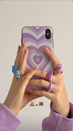 a woman holding up her cell phone to take a selfie with two rings on it