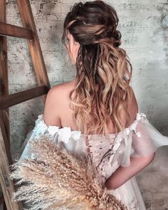 a woman in a white dress is sitting on a chair with her hair pulled back