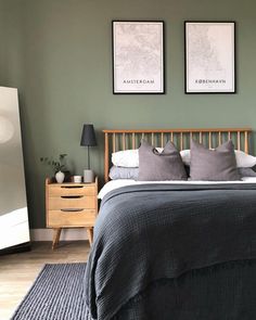 a bedroom with green walls and two pictures on the wall above the bed, along with a black rug