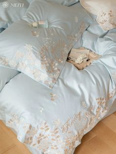 the comforter is blue and has gold embroidered designs on it, along with two pillows