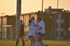 a group of young women standing on top of a soccer field