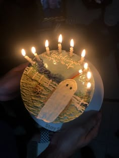 a birthday cake with candles in the shape of a ghost is being held by someone