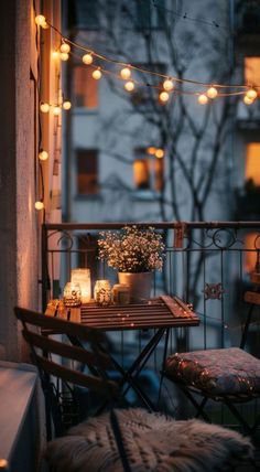 a balcony with lights strung from the ceiling and a small table on it, next to a chair