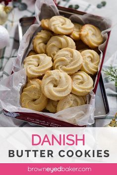 danish butter cookies in a red tray on a table with christmas decorations and greenery