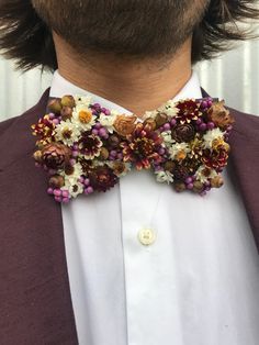 a close up of a man wearing a bow tie with flowers on it