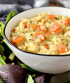 a white bowl filled with food next to lettuce and carrots