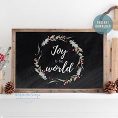 a chalkboard with the words joy to the world written on it and pine cones