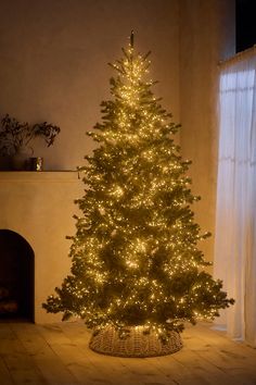 a lit christmas tree sitting in front of a fireplace