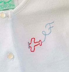 a white shirt with red and blue stitching on it