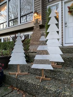 three wooden christmas trees sitting on top of steps