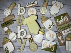 baby shower cookies are laid out on a wooden table with green and white onesuits