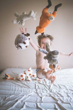 a young child playing with stuffed animals on a bed