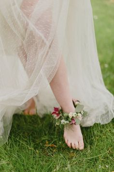 a bride's feet in the grass with flowers