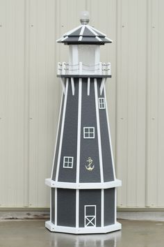 a black and white lighthouse shaped object sitting on top of a cement floor next to a building