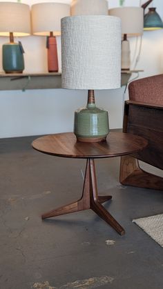 a lamp sitting on top of a wooden table next to a chair and ottoman in a room