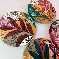 four colorful plates with leaves painted on them