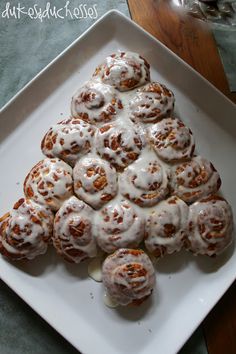 a white plate topped with cinnamon rolls covered in icing