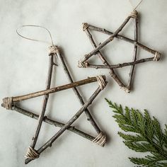 three wooden sticks are hanging from twine on a table next to a pine branch