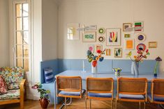 a dining room table with four chairs and vases on the wall next to it