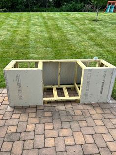 an unfinished kitchen cabinet sitting on top of a brick floor in the middle of a yard