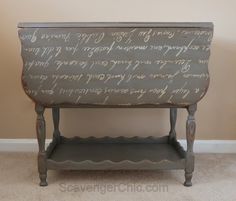 an old wooden table with writing on it and a shelf below the top that has wine bottles