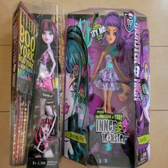 two monster high dolls in their packaging on the floor next to each other and one is wearing a purple dress