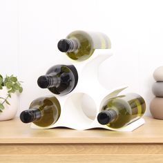 several bottles of wine sitting on top of a wooden table next to rocks and a potted plant