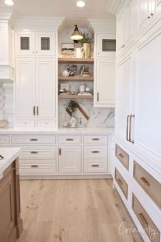 a kitchen with white cabinets and wood flooring in the center, along with marble counter tops