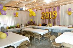 a room filled with tables covered in white tablecloths and balloons