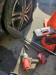 tools are laying on the ground next to a car