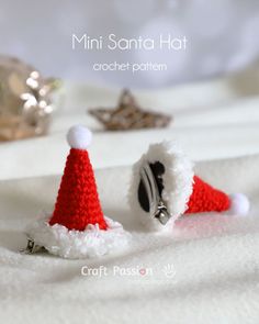 two crocheted santa hats sitting on top of a white blanket next to a diamond