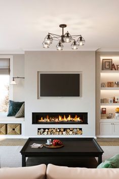 a living room with a couch, coffee table and fire place in front of a flat screen tv